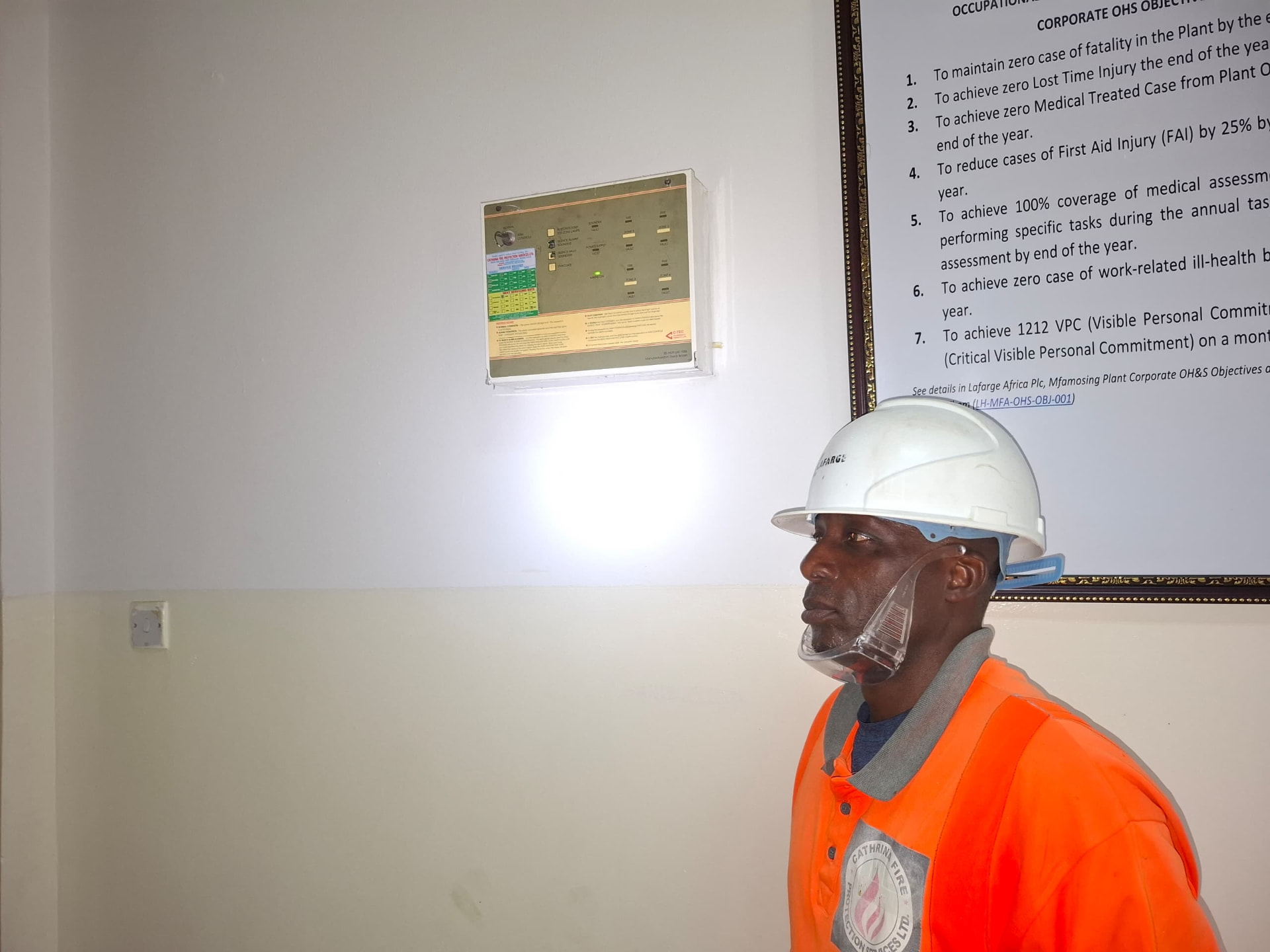 Technician inspecting an installed fire alarm control panel at a plant